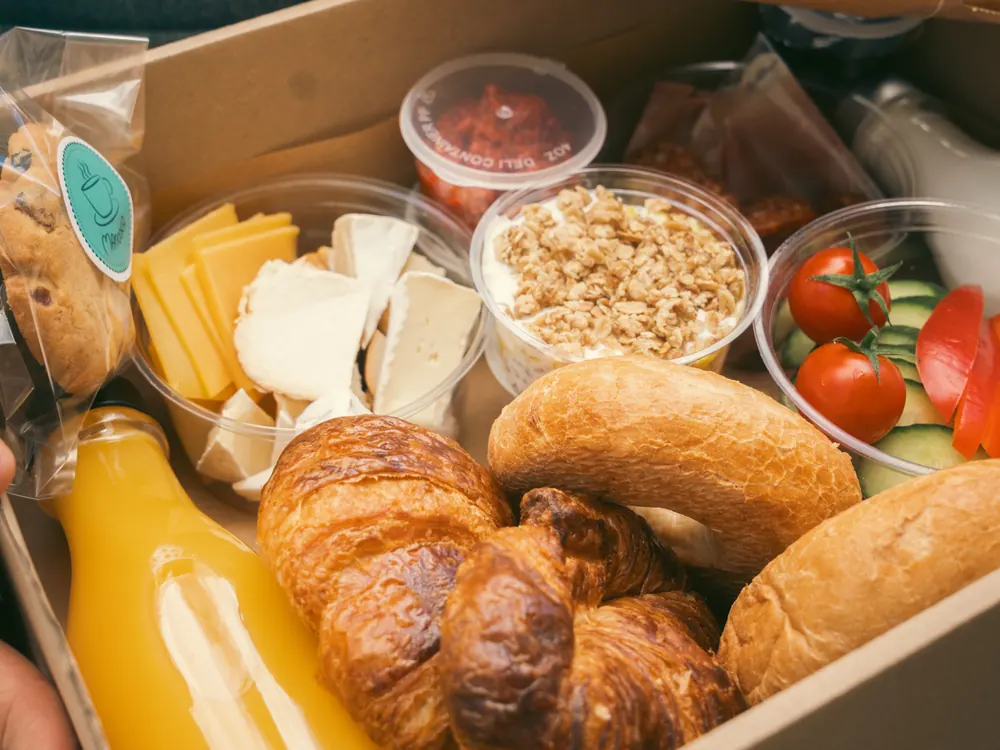 Piknik box a fűben: croissant, bagel, sajt, zöldség, narancslé