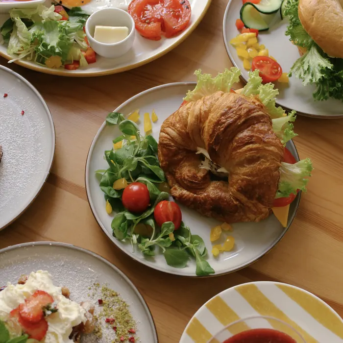 Tálalt falatok, croissant és saláta egy közös asztalon