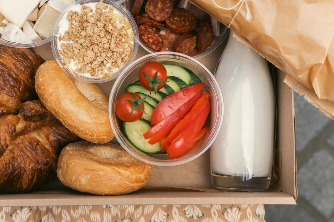 Croissant, bagel, friss zöldség és tej egy dobozban, helyi alapanyagokból
