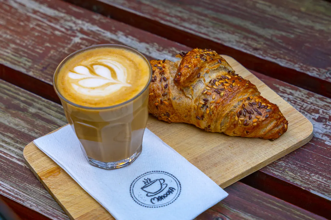 Specialty latte és vajas croissant fa tálcán, Manooka Kávézó
