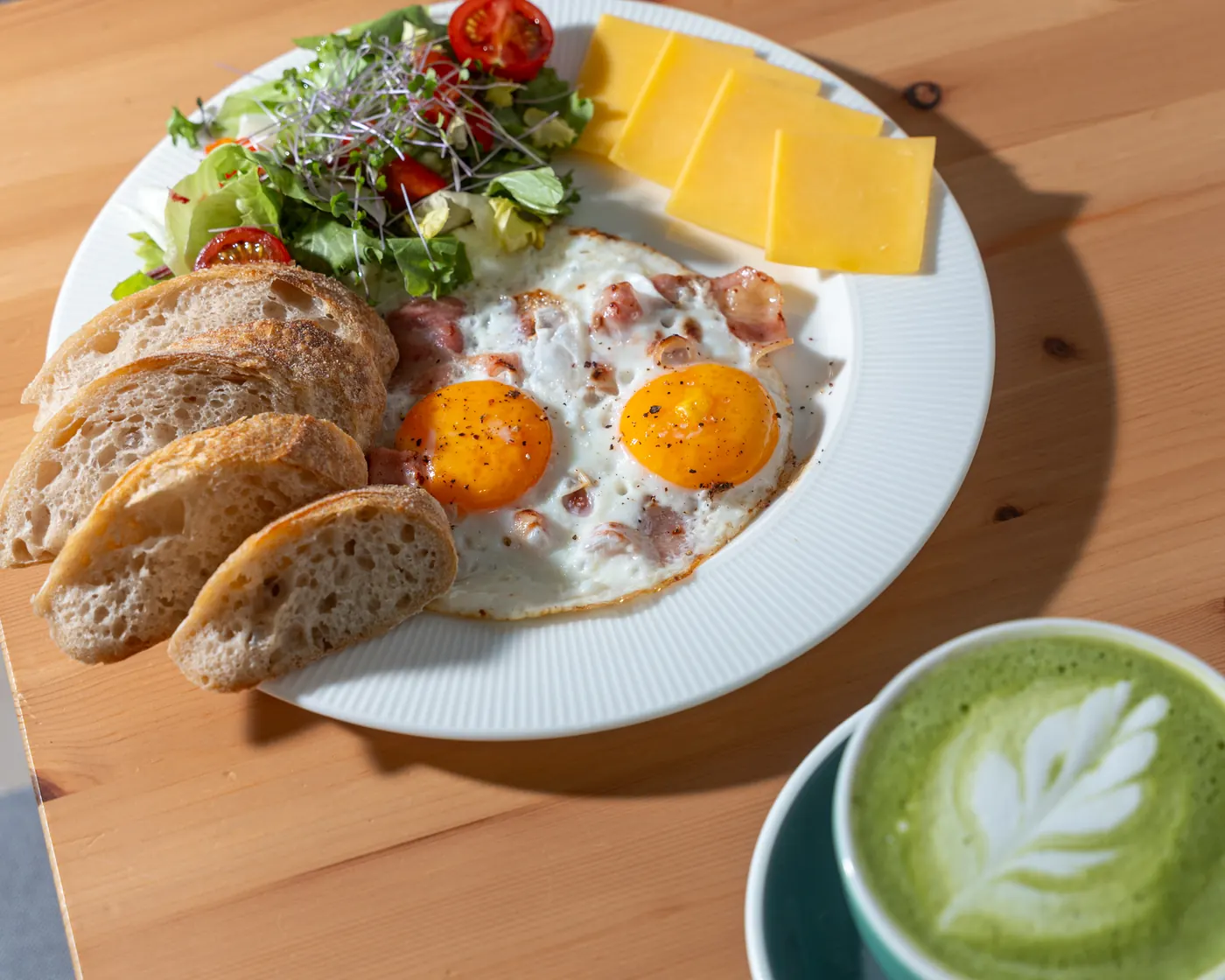 Tükörtojásos reggeli tál pirított kenyérrel, sajttal és matcha lattéval a Manooka asztalán, Eger