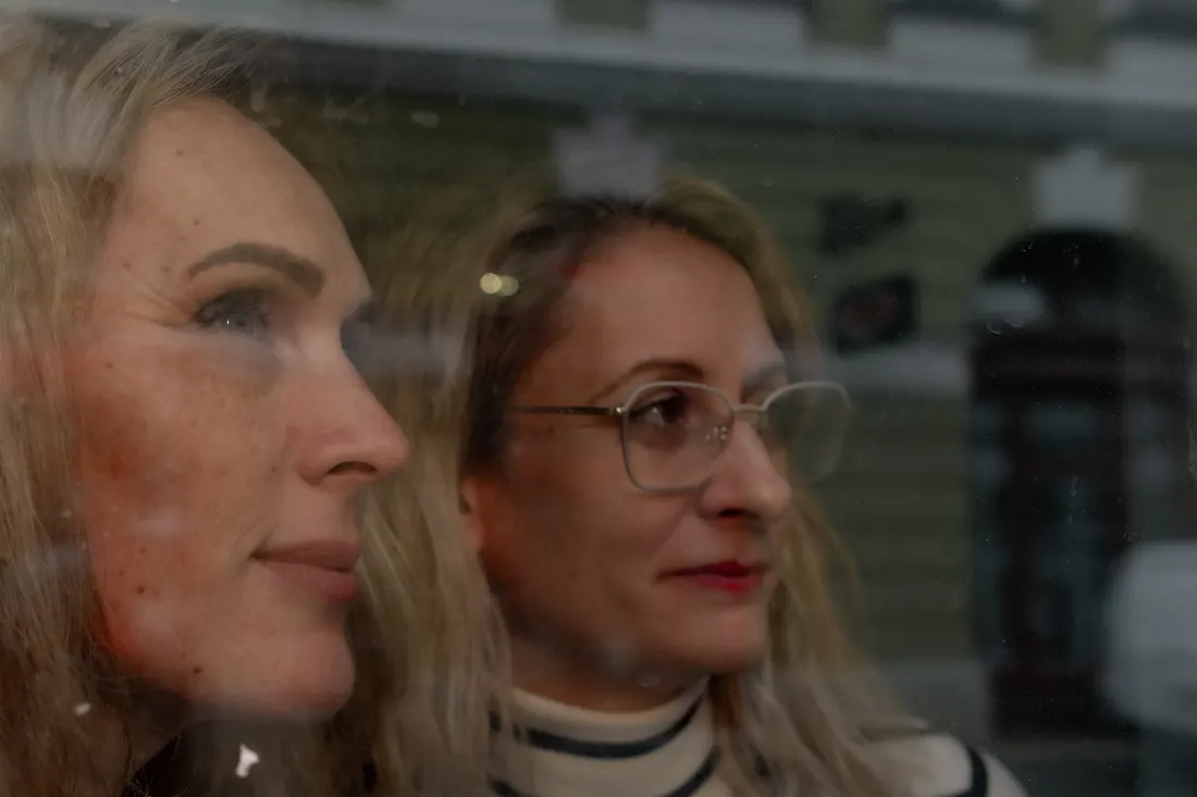 Két munkatárs mosolyog a kávézó ablakában